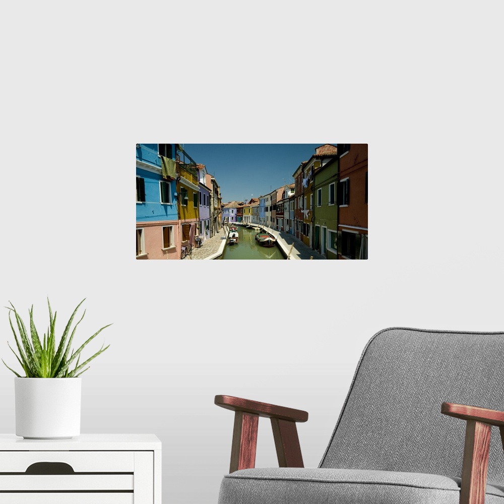 A modern room featuring Colorful buildings line either side of a canal in Italy.