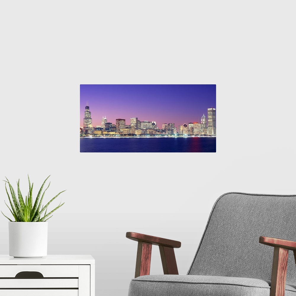 A modern room featuring Large photo on canvas of a lit up cityscape by the waterfront at dusk.