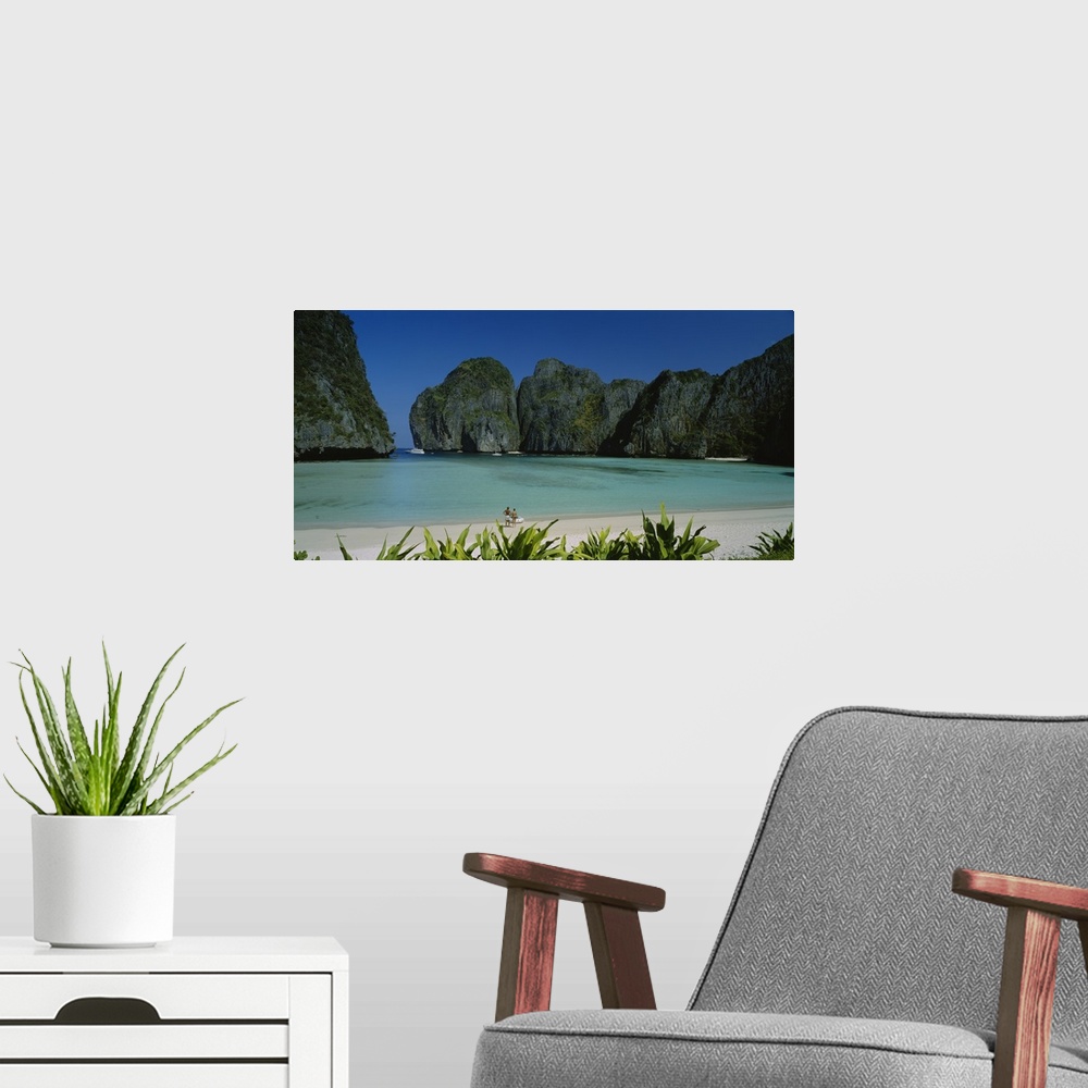 A modern room featuring A breathtaking photograph of a beach in Thailand surrounded by mountains with a couple at the edg...