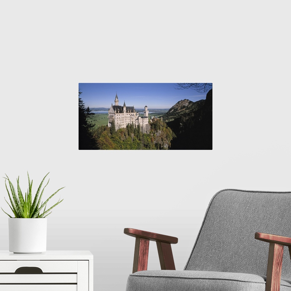 A modern room featuring A landscape photograph of an elegant caste build on top of a steep, tree covered hill.