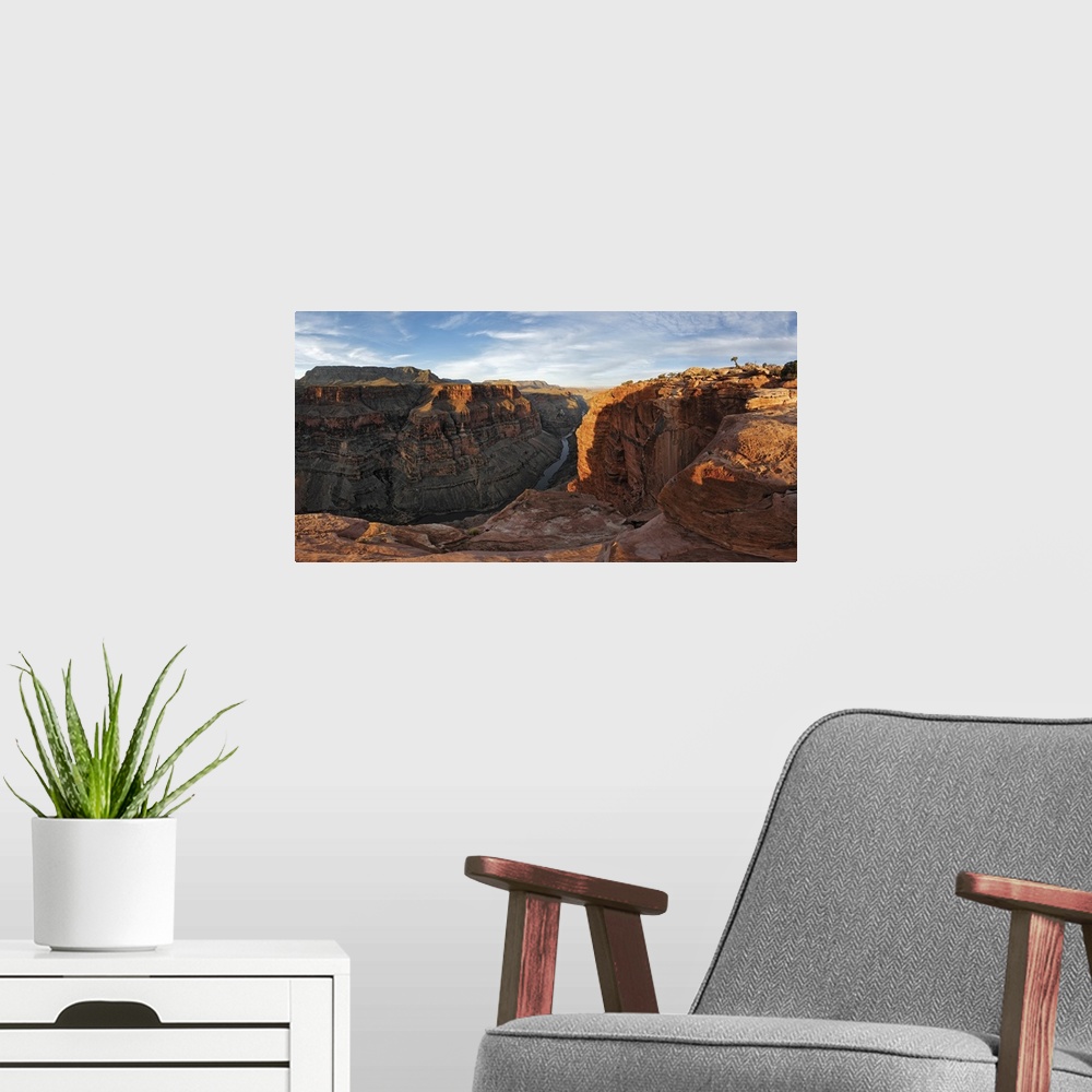 A modern room featuring Large canvas photo of Grand Canyon cliffs draped in sunlight and shadows with a river running thr...
