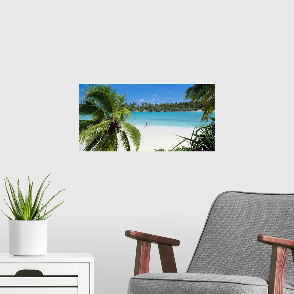 A modern room featuring Photograph of a lady walking alone on a white sand beach surrounded by crystal clear water and pa...