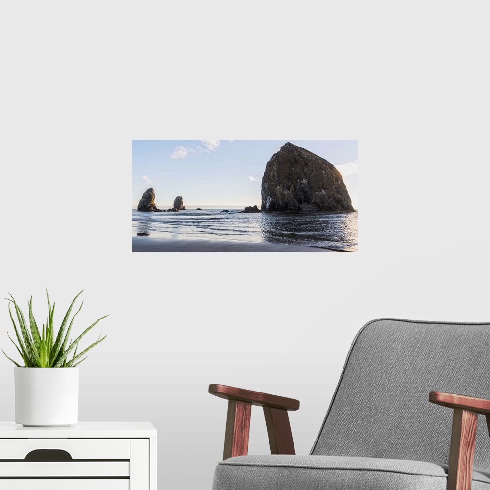 A modern room featuring Panoramic photograph of Haystack Rock at Cannon Beach with blue skies.