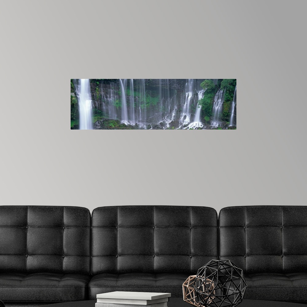 A modern room featuring Wide angle, photograph on a large canvas of Shiraito Falls, surrounded by greenery, in Fujinomiya...