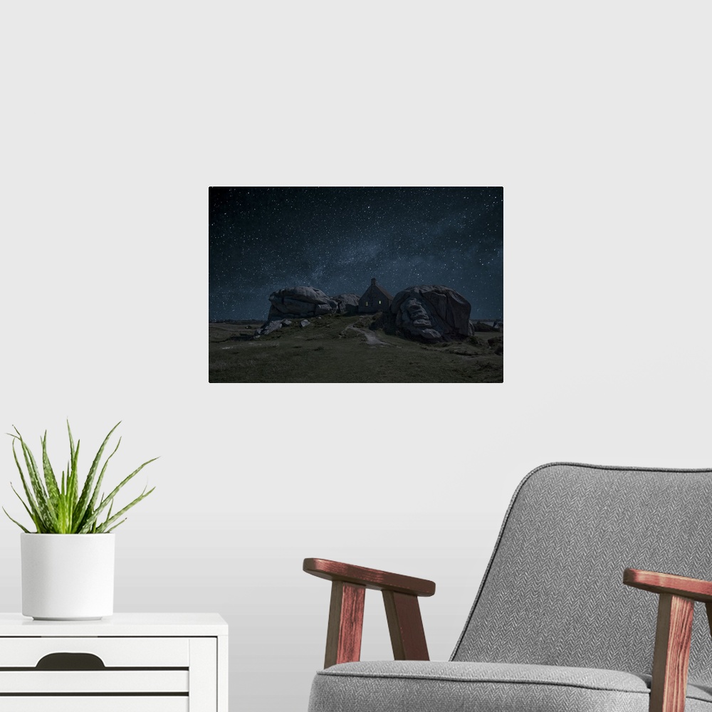 A modern room featuring A small house nestled between large rock formations under a night sky full of stars.