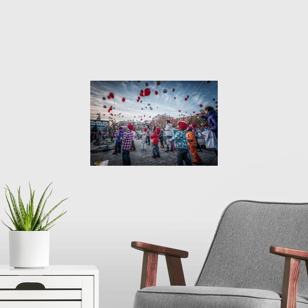 A modern room featuring Crowd of people releasing silver and red balloons into the air to celebrate the new year.