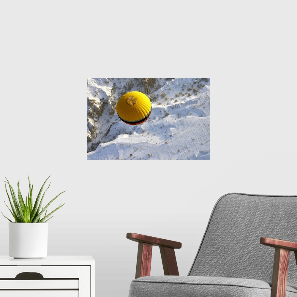 A modern room featuring A yellow hot air balloon floats above the snow covered landscape of Cappadocia, Turkey.