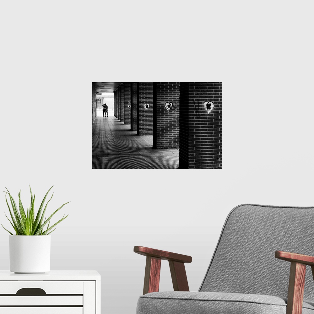 A modern room featuring Black and white photograph with leading lines from brick columns with spray painted hearts on the...