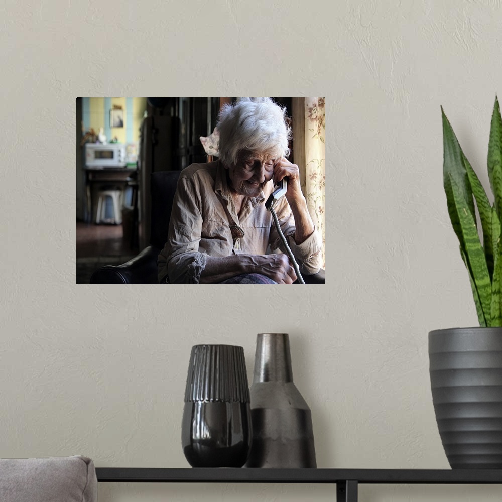A modern room featuring Portrait of an elderly woman talking on a corded telephone.
