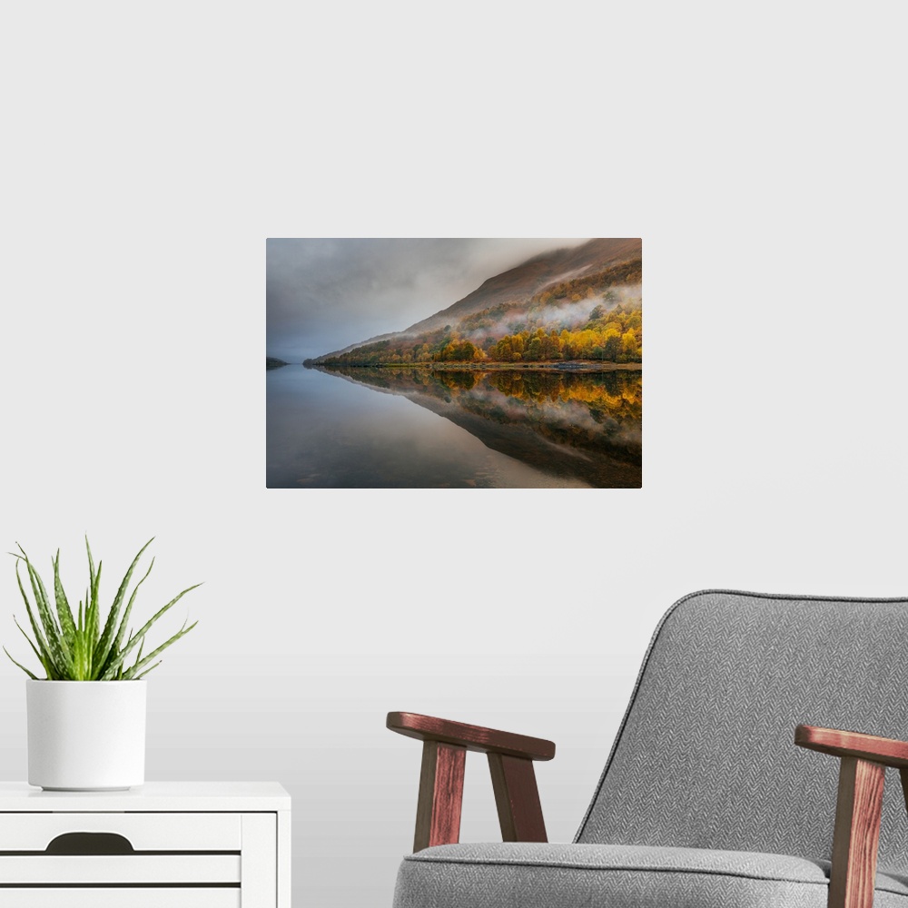 A modern room featuring Landscape photograph of reflective Autumn mountains with light fog on a lake.