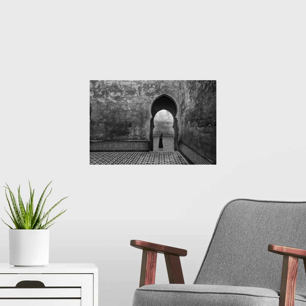 A modern room featuring A black and white photograph of a man passing by an archway.
