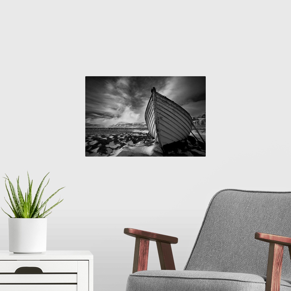 A modern room featuring A black and white photograph of a row boat on the shore of an Icelandic beach.