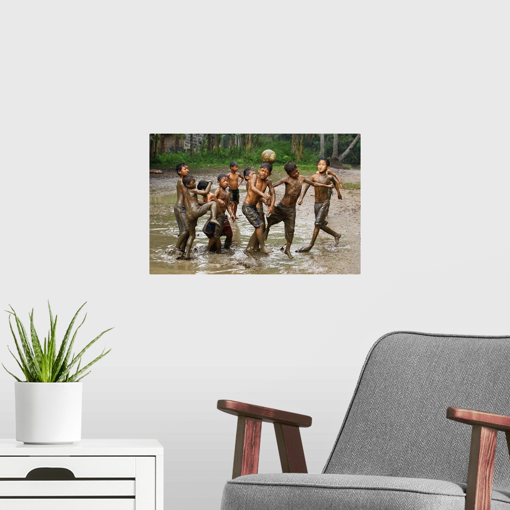A modern room featuring A group of young boys playing soccer in muddy water.