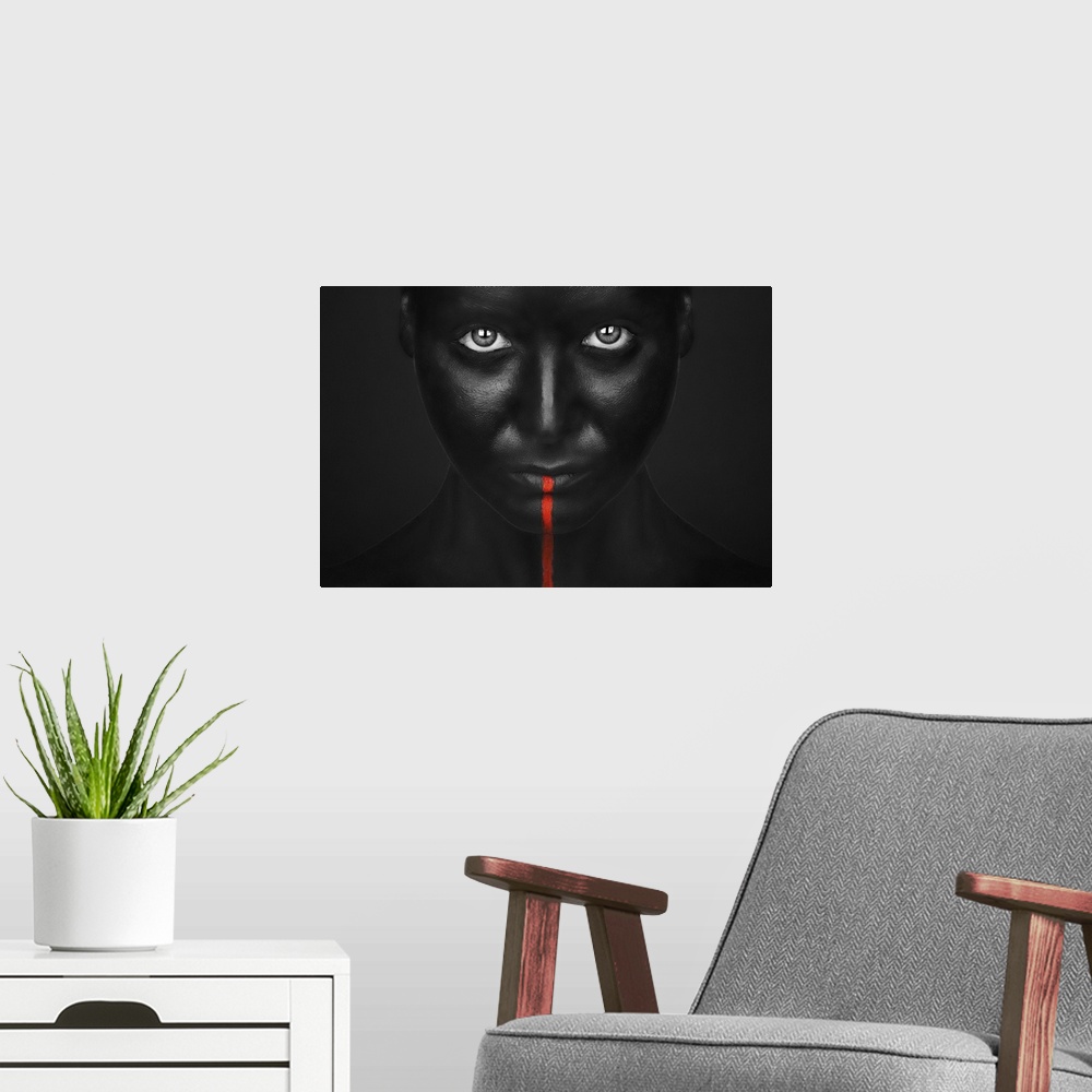 A modern room featuring A person with completely black bodypaint covering their face with a single red stripe running dow...