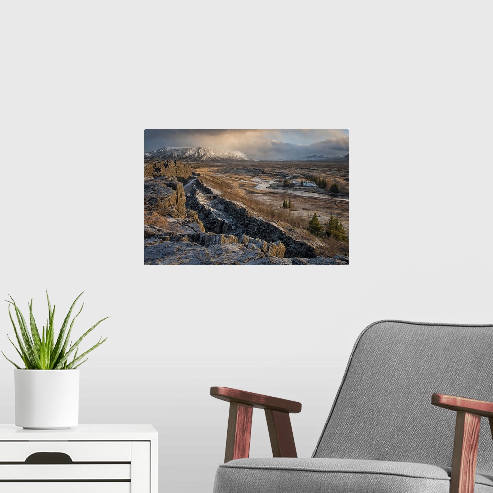A modern room featuring A small village can be seen in the distance of this desolate looking Icelandic rift valley.