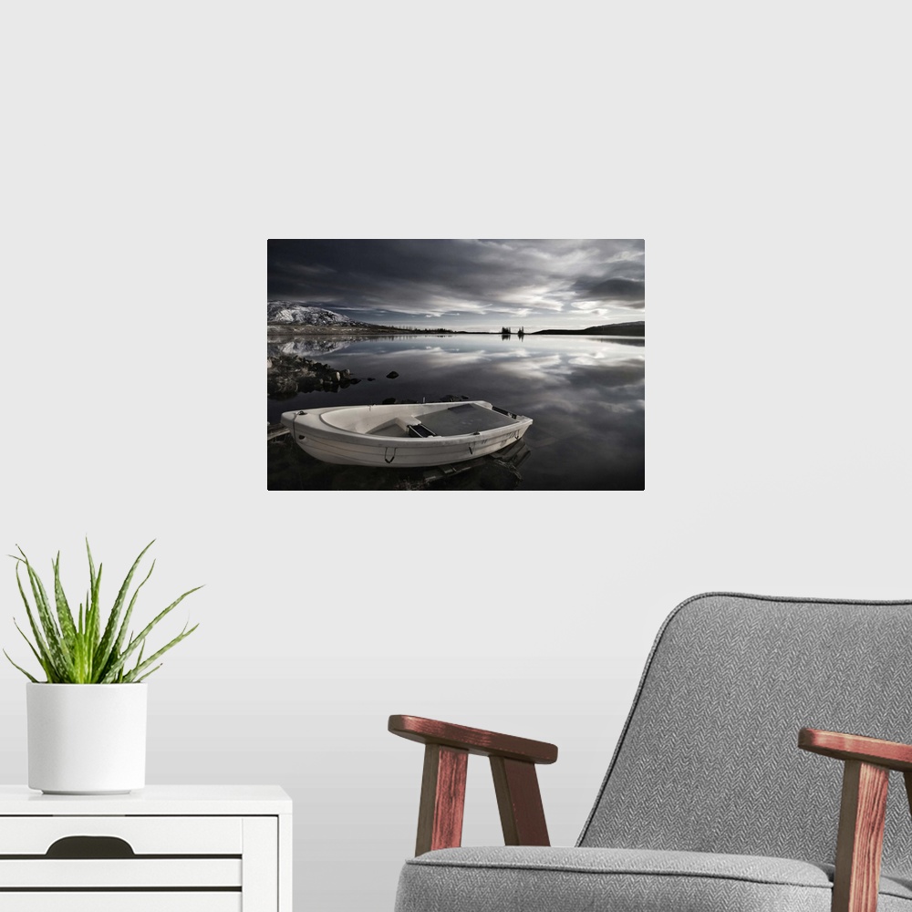 A modern room featuring A small boat on the edge of a still lake, Iceland.
