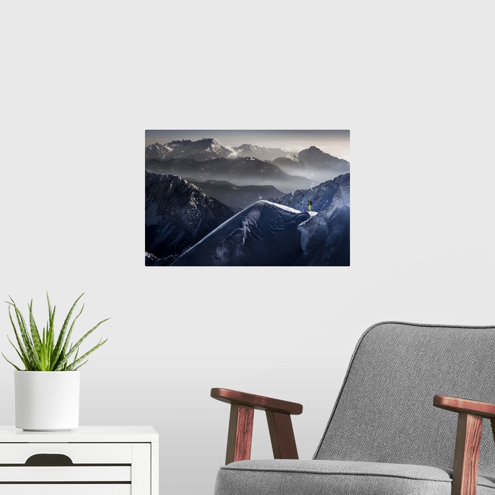 A modern room featuring A skier pauses at the top of a mountain, with peaks of neighboring mountains in the background.