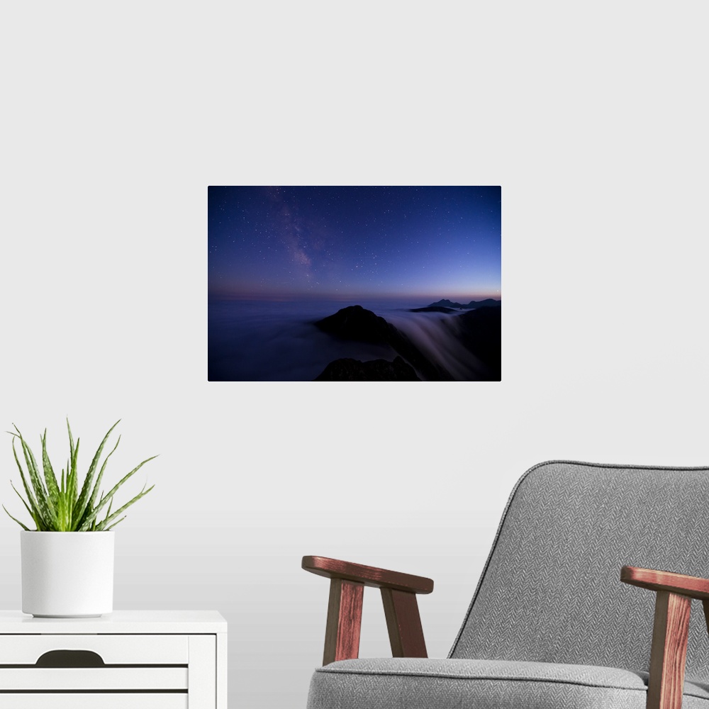 A modern room featuring Skyscape in the evening with stars, above a misty mountain range.