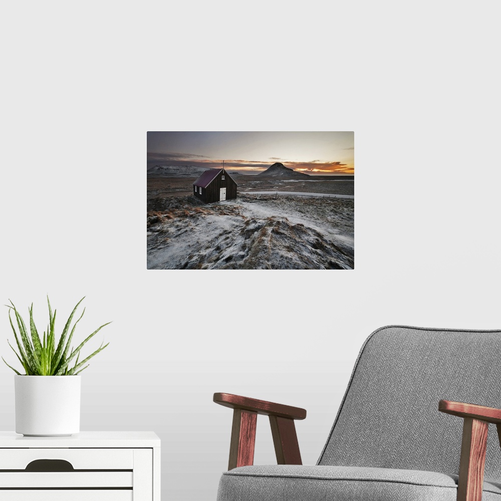 A modern room featuring Small church in the icy rural landscape of Iceland, during sunset.
