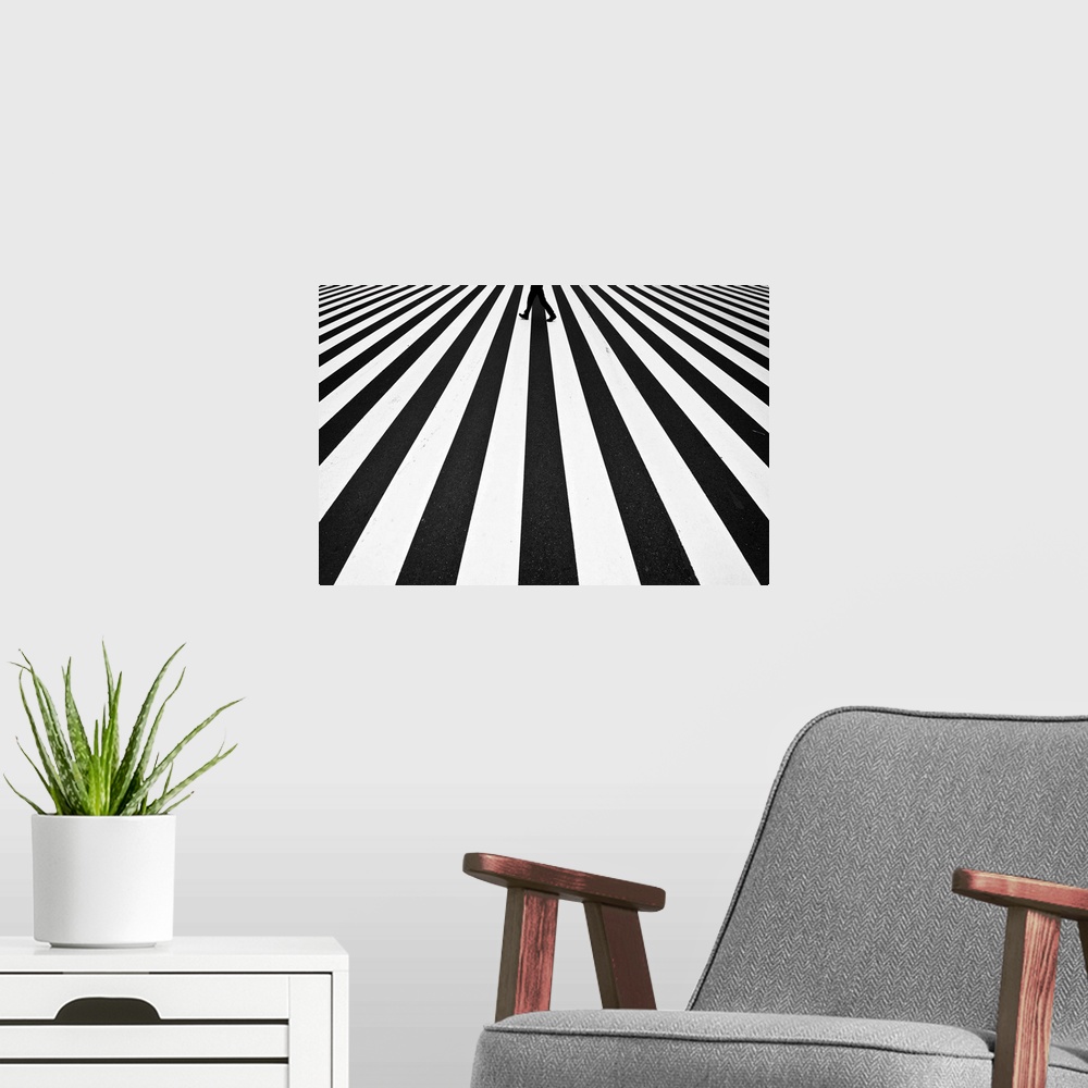 A modern room featuring A pattern created by a zebra crossing in the street is broken by a figure walking across.