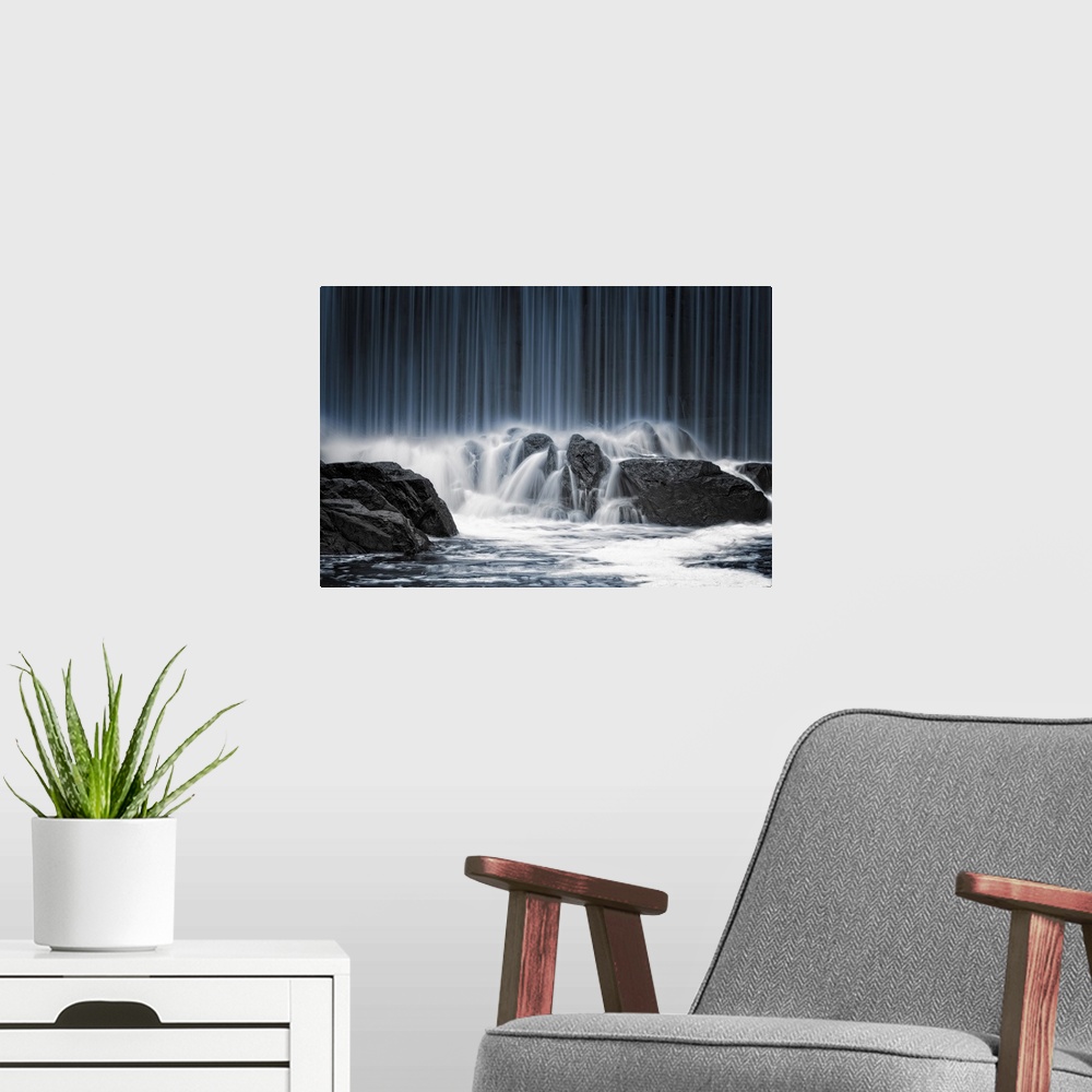 A modern room featuring A waterfall pouring down over a massive boulders.