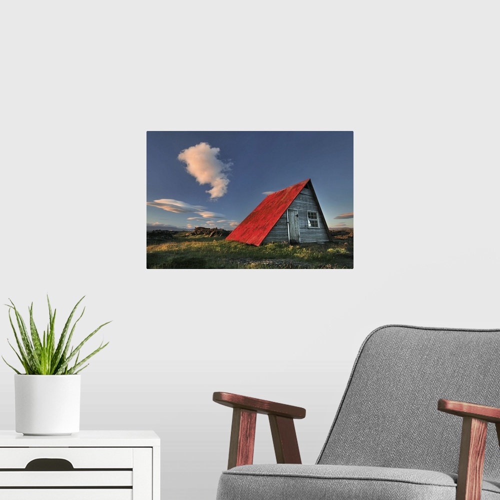 A modern room featuring a wooden hut in Iceland with a bright red roof, seen at sunset.