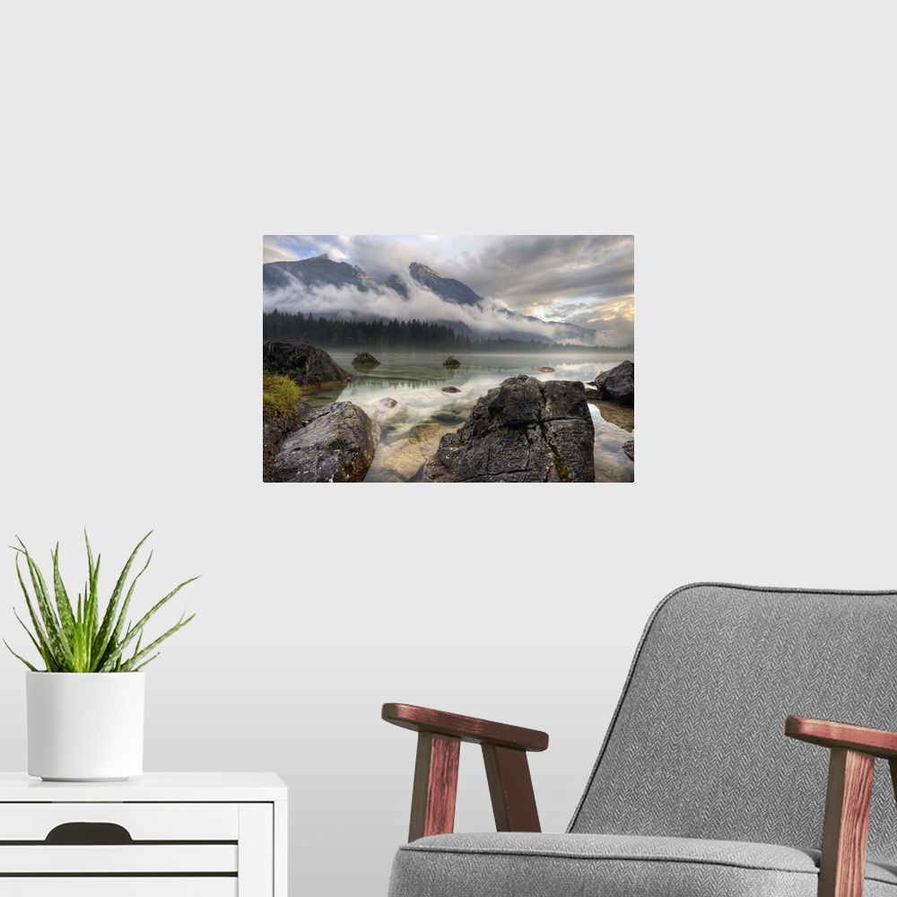 A modern room featuring Rocks on the shore of a lake below mountains obscured by clouds, Germany.