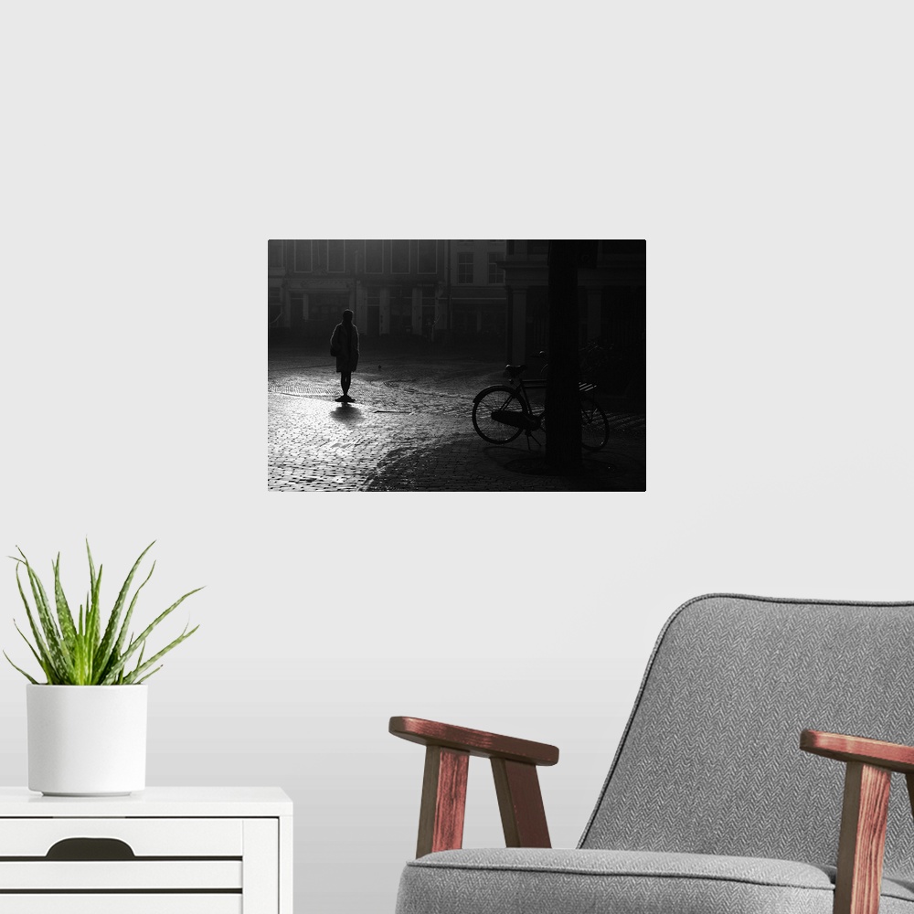 A modern room featuring A silhouetted woman standing in a street near a bicycle, Haarlem, Netherlands.