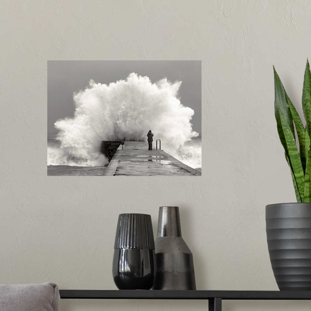 A modern room featuring A photographer standing on a pier with waves crashing.