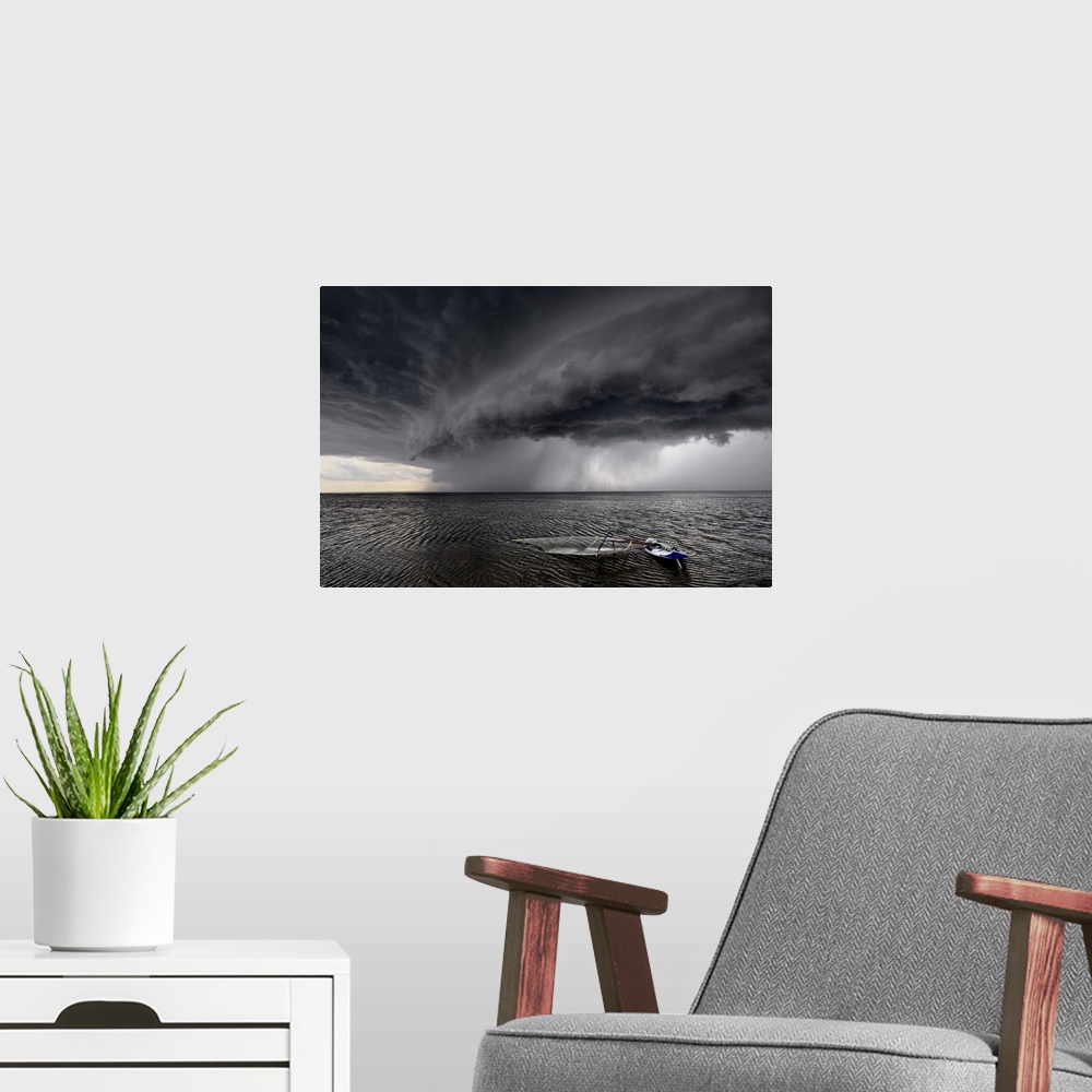 A modern room featuring A windsurfing board lays flat in the water as stormclouds with heavy rain approach.