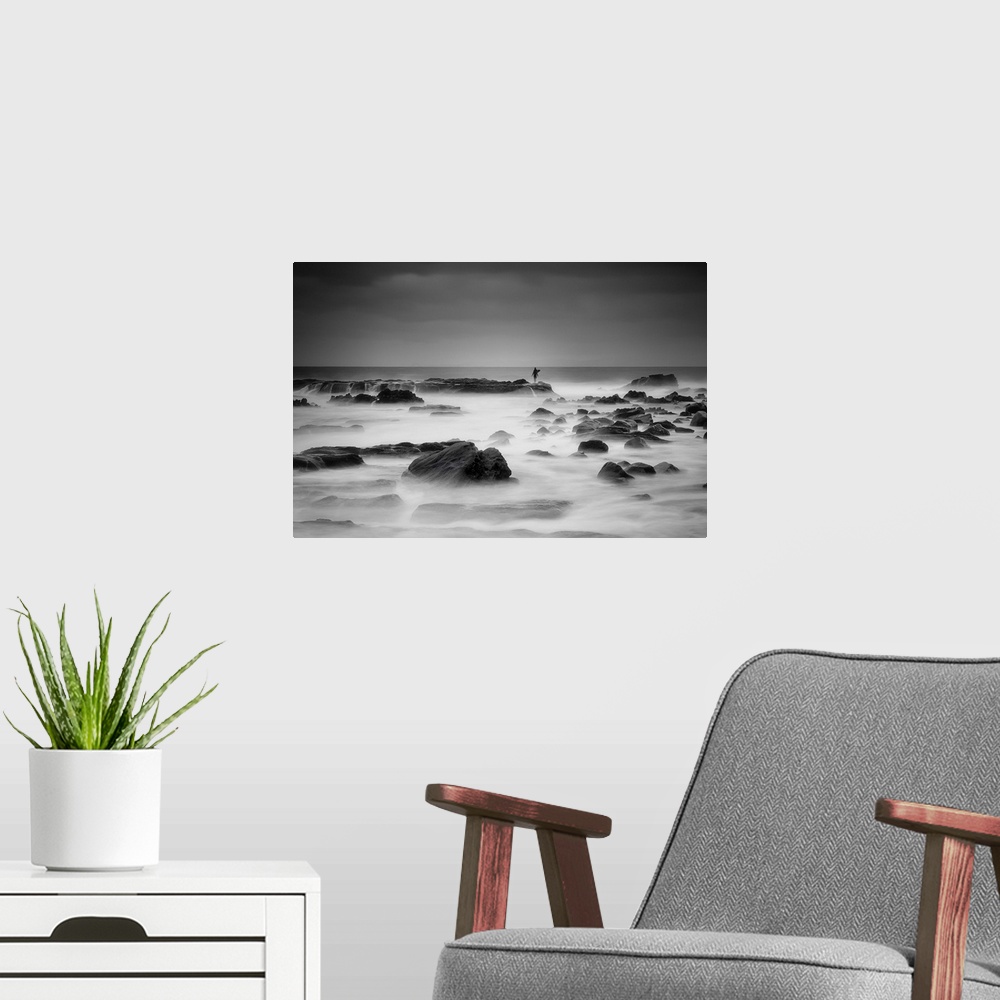 A modern room featuring A figure stands in the distance on a rock protruding from the misty ocean.