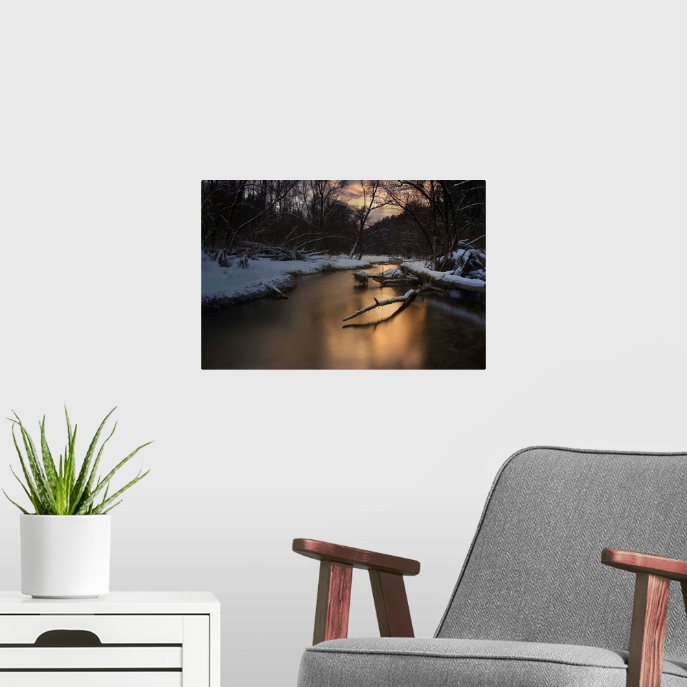 A modern room featuring A serene river reflecting evening light in a snowy forest in the winter.