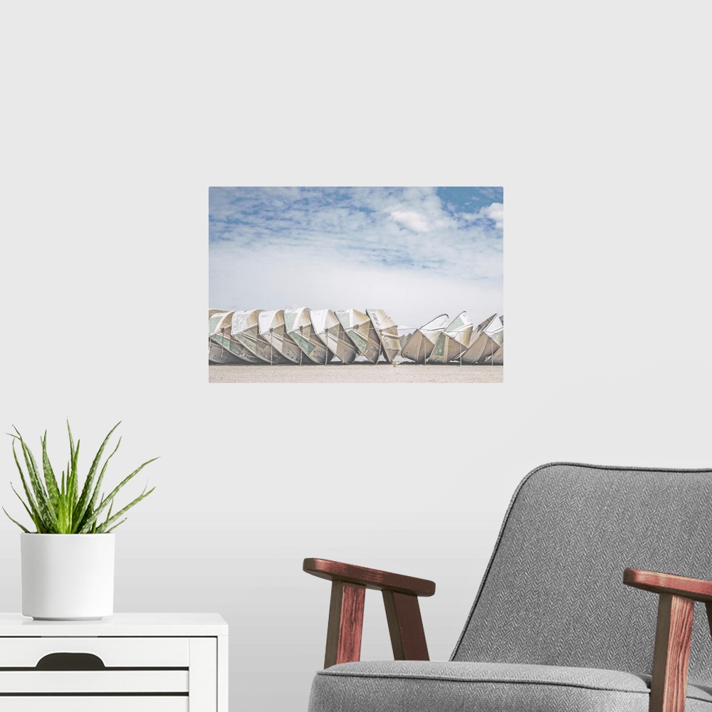 A modern room featuring A fine art photograph of a row of identical small boats leaned against each other, with a very co...