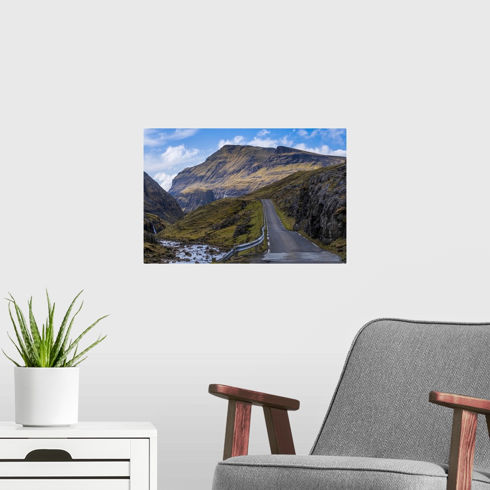 A modern room featuring A scenic empty straight uphill road leading to Saksun on the Faroe Islands.