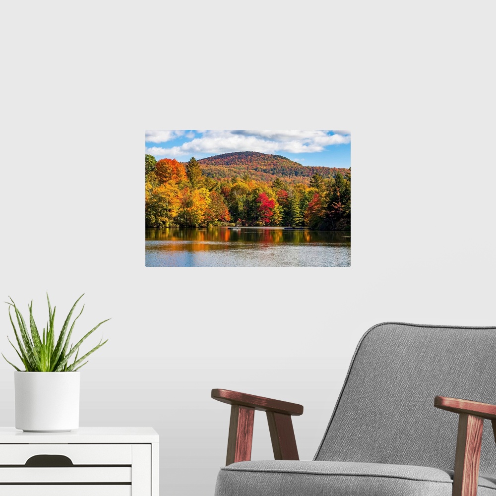 A modern room featuring Autumn coloured trees in a forest around a small lake, Sally's Pond, Quebec, Canada.