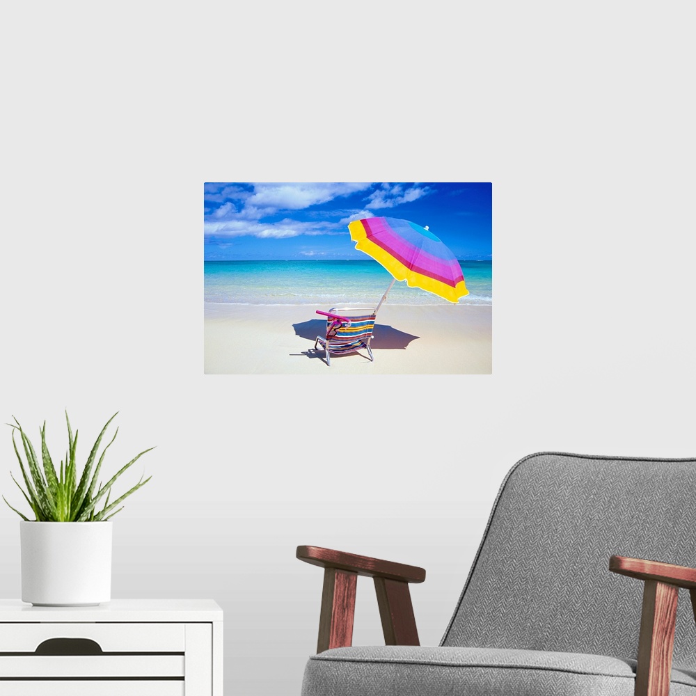 A modern room featuring A large photograph of a colorful beach chair and umbrella sitting solely on the sand close to the...