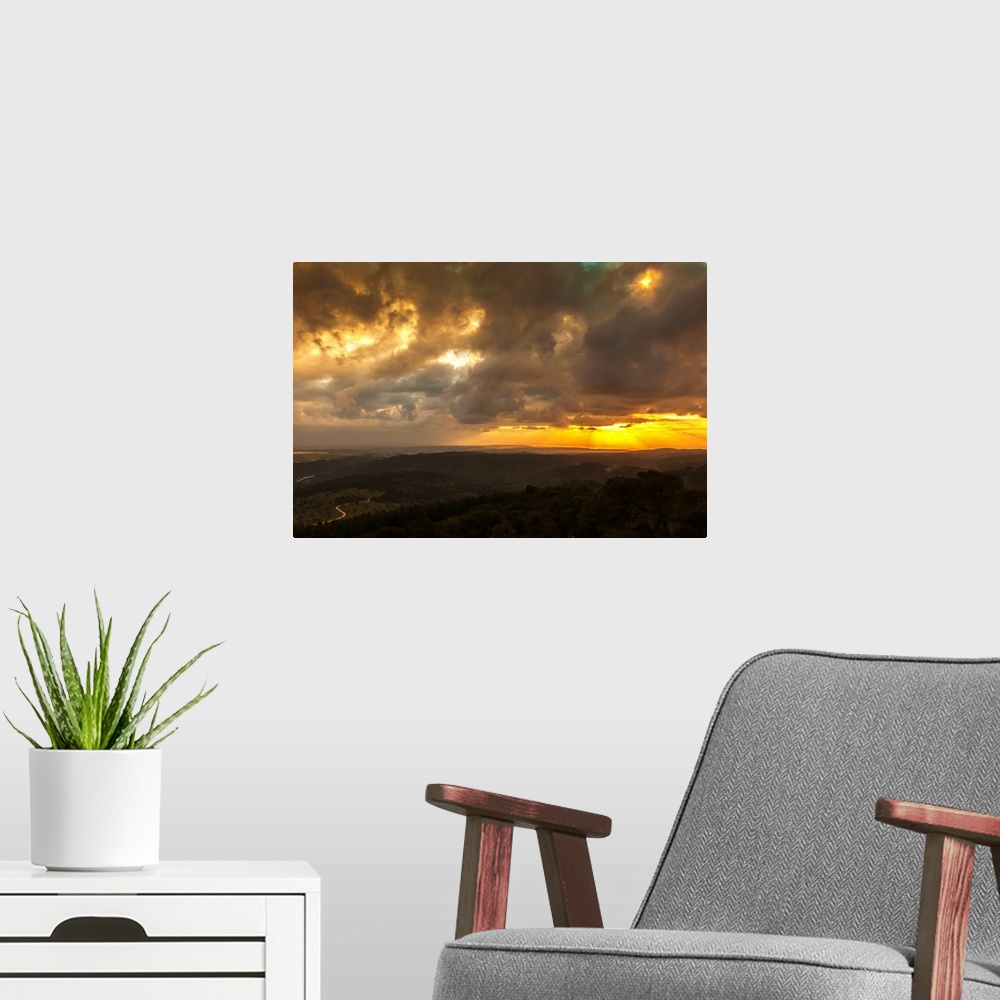 A modern room featuring Golden sunset with glowing clouds and silhouetted landscape. Israel.