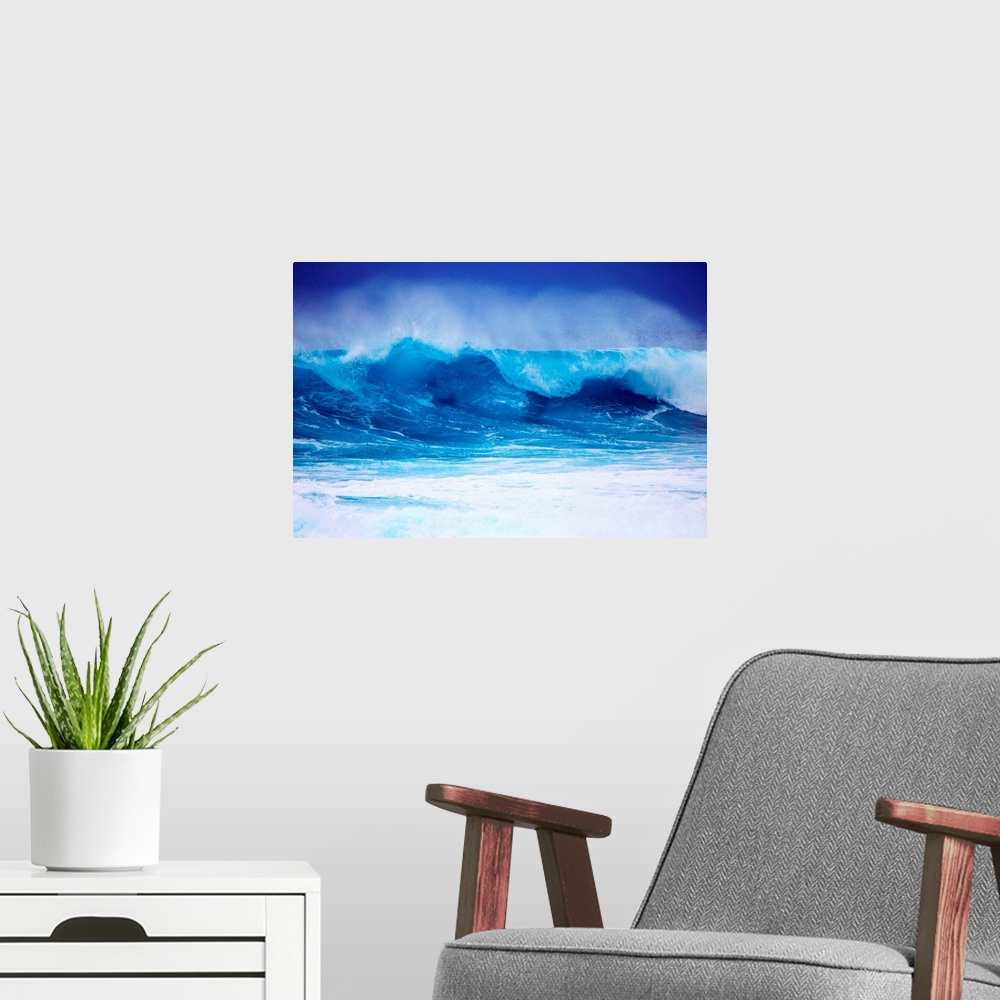 A modern room featuring Giant horizontal photograph of a vibrant blue wave spraying upward as it begins to crash onto its...