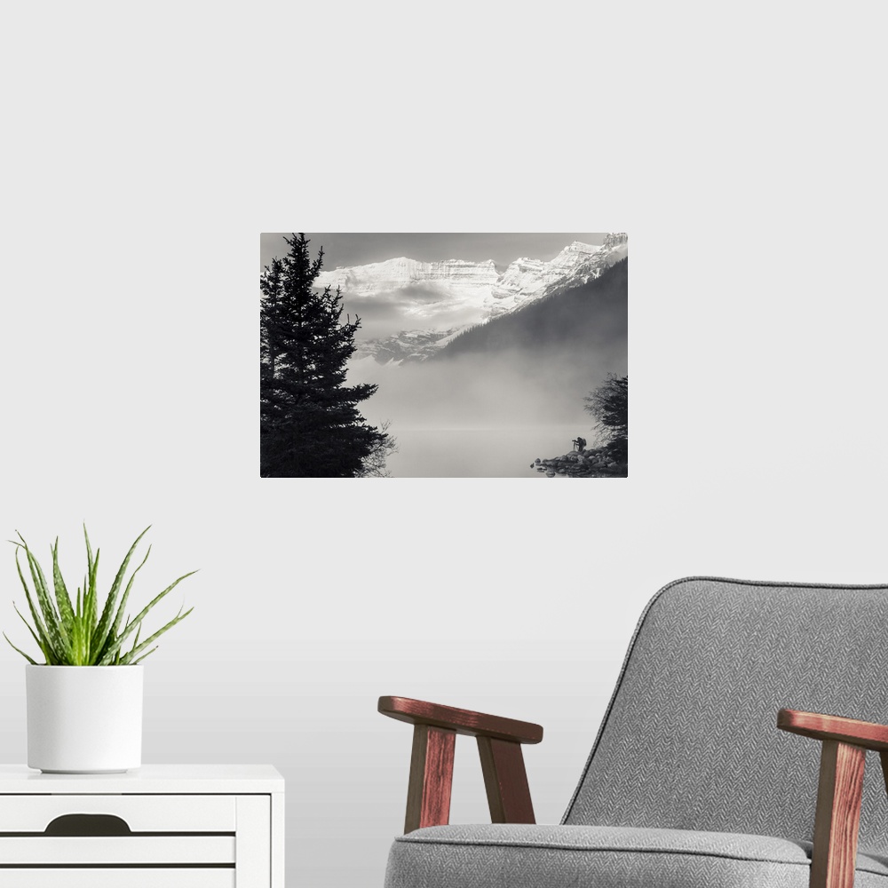 A modern room featuring Silhouette of a photographer on the shore of Lake Louise with fog rising from the lake at sunrise...