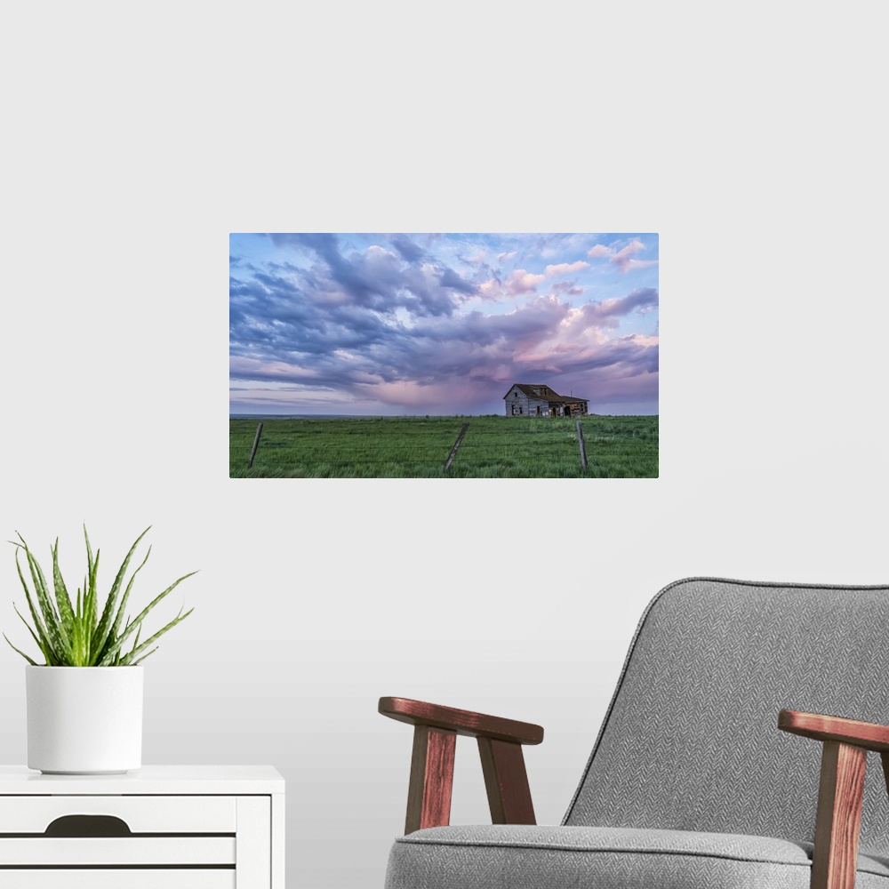 A modern room featuring Old farmstead on the prairies under glowing storm clouds at sunset; Val Marie, Alberta, Canada