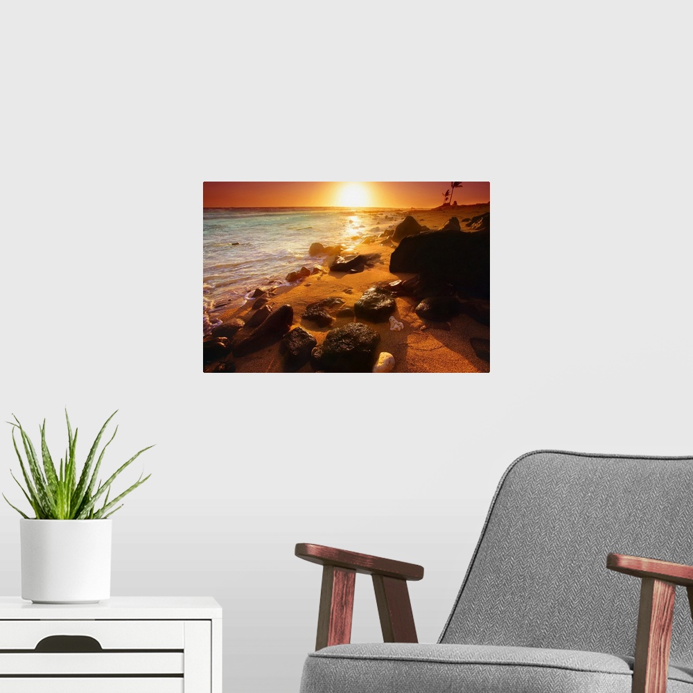 A modern room featuring Photograph taken of a sunset on the ocean horizon with various rocks spread out on the beach in t...