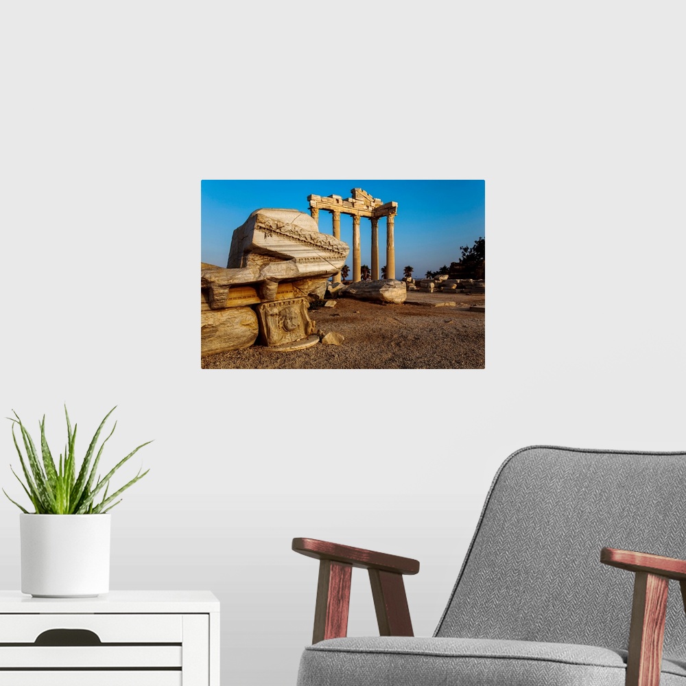 A modern room featuring Roman and Hellenistic ruins of the Temple of Apollo under a bright blue sky at sunrise, a ruined ...