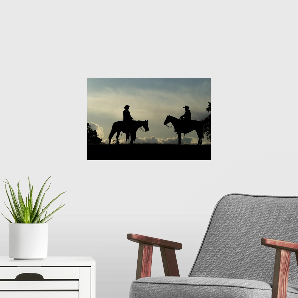 A modern room featuring Silhouette of two cowboys on horses against a cloudy sky; Montana, United States of America.