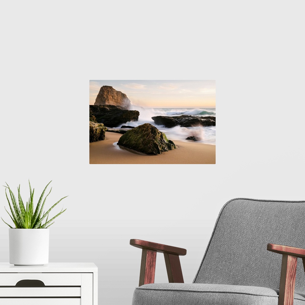 A modern room featuring Sunset along the central California coast with waves crashing onto the large rocks on the beach S...