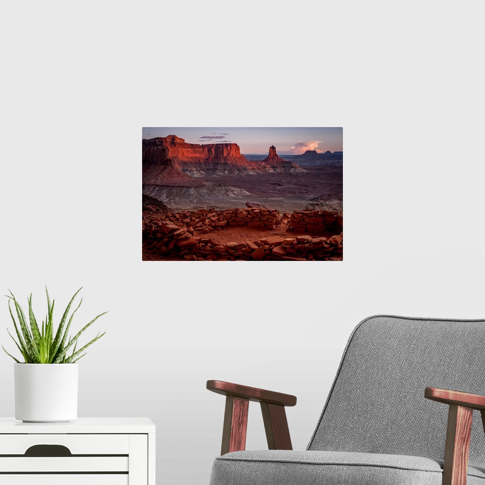 A modern room featuring Landscape photograph of stacked rocks creating a circle with canyons in the background at sunrise.