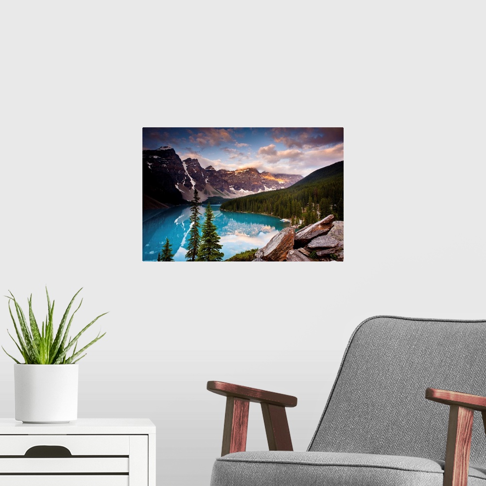A modern room featuring Landscape photograph of Lake Moraine surrounded bu snowy mountains and pine trees.