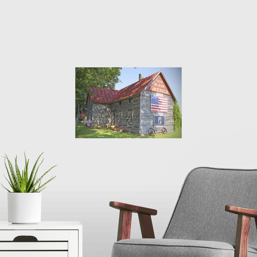 A modern room featuring A photograph of a rustic country home with an American flag on the side.
