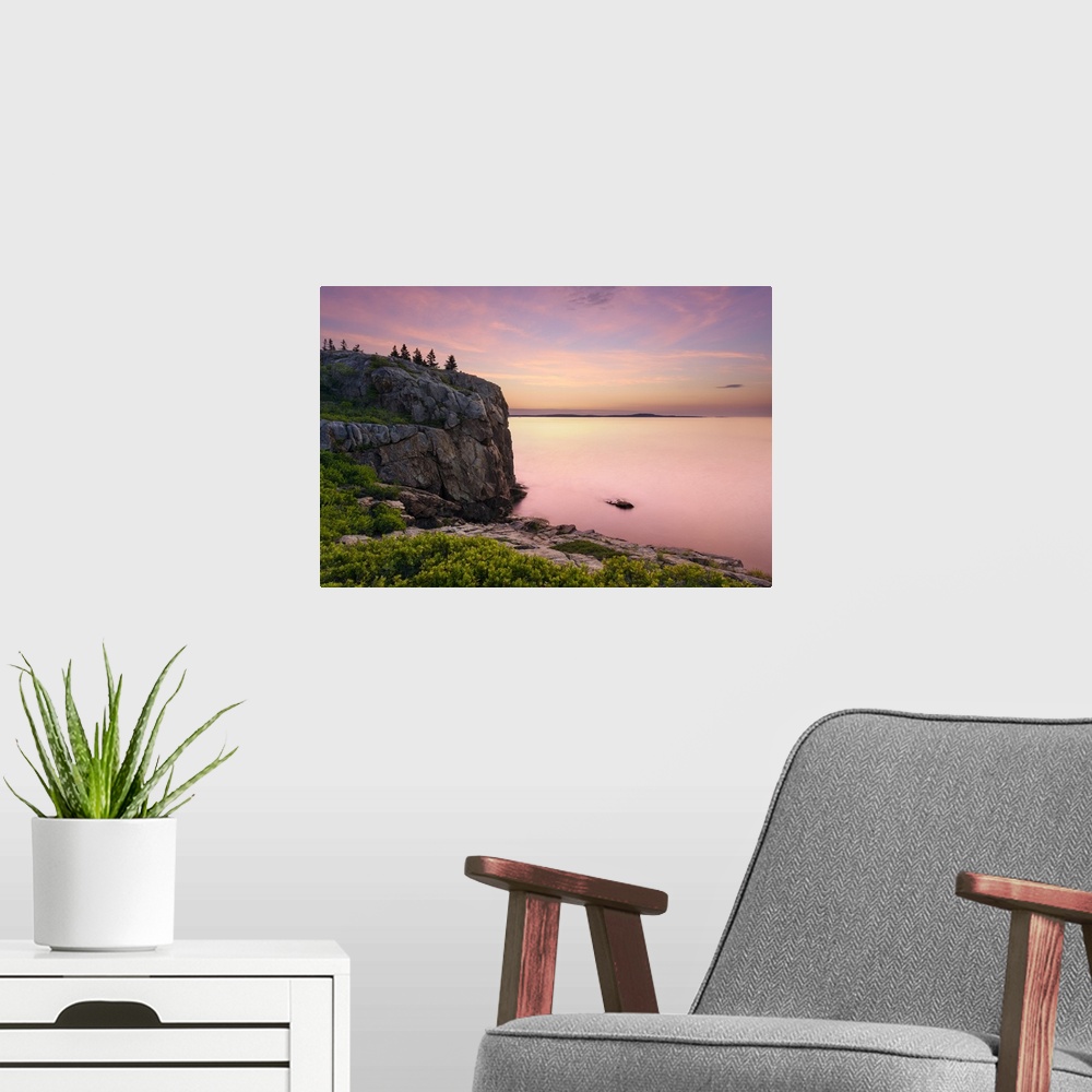 A modern room featuring An artistic photograph of a rocky cliff-side overlooking a sunset drenched seascape.