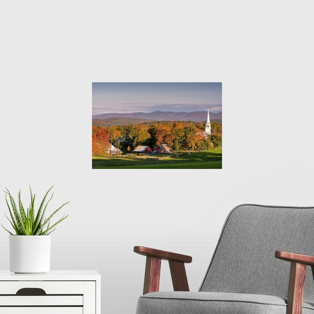 A modern room featuring A photograph of the steeple of a white church sticking high up out of the autumn colored forest.
