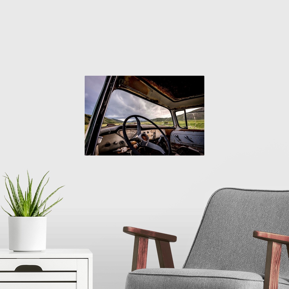 A modern room featuring Photograph of the inside of an old abandoned car full of rust in the middle of a valley.